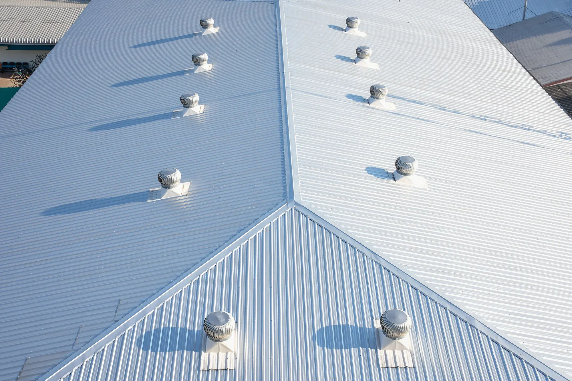 Standing seam metal roof seen from above, panels running unbroken to the ridge